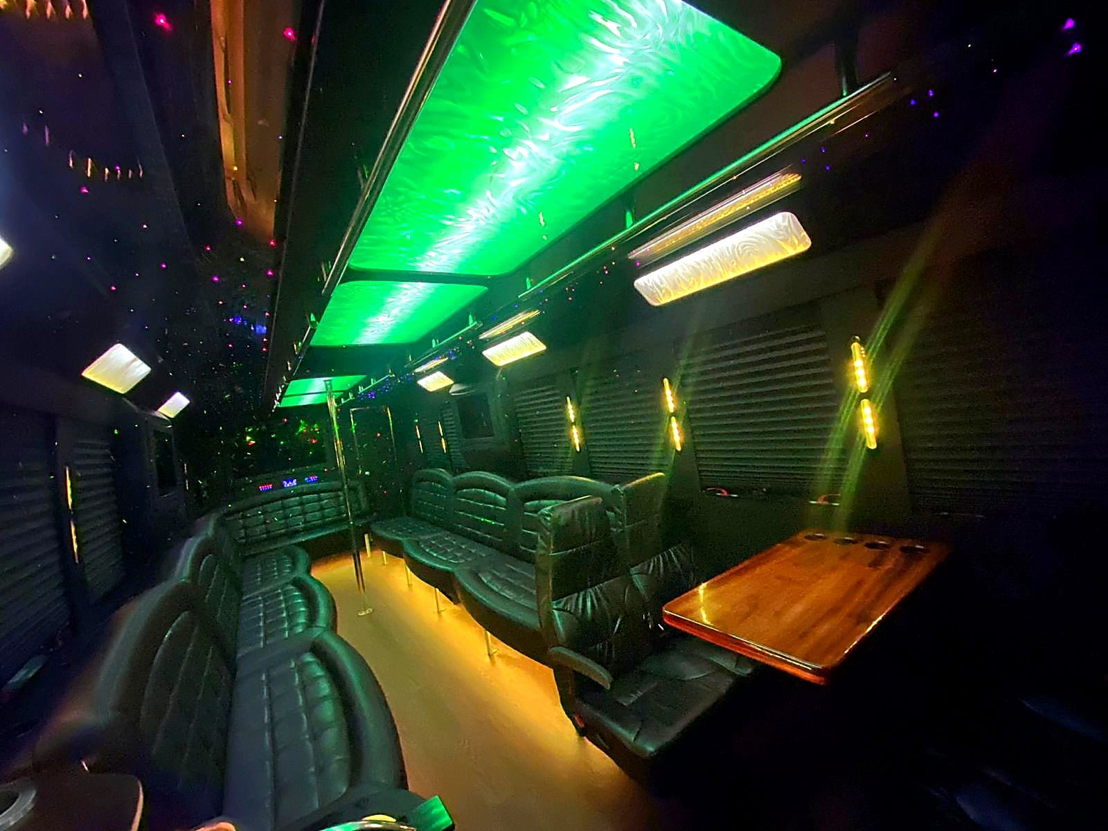 Emerald green LED party bus interior with captain chair and wood table